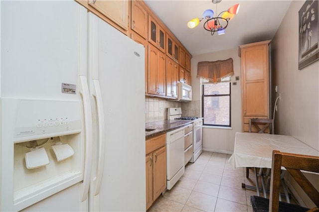 kitchen with a chandelier, light tile patterned floors, pendant lighting, white appliances, and backsplash