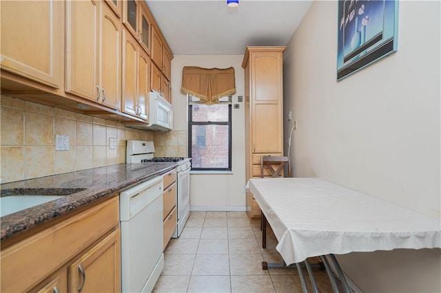 kitchen featuring light tile patterned flooring, white appliances, and dark stone countertops