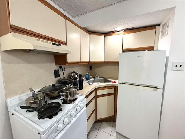 kitchen with sink, white cabinetry, a textured ceiling, light tile patterned floors, and white appliances