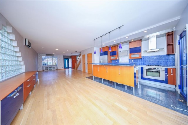 kitchen featuring wall oven, light wood-type flooring, wall chimney exhaust hood, tasteful backsplash, and stainless steel fridge