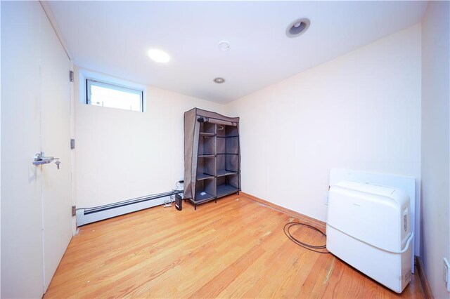 interior space with a baseboard heating unit and light hardwood / wood-style floors