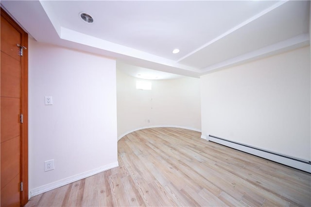 unfurnished room featuring light hardwood / wood-style floors, a raised ceiling, and baseboard heating