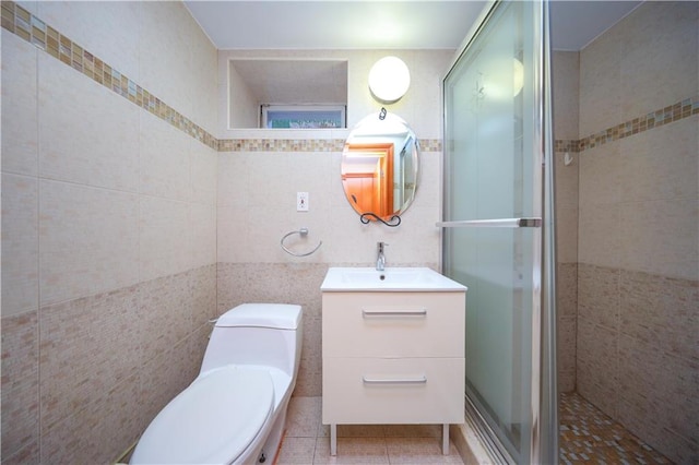 bathroom with tile walls, toilet, a shower stall, vanity, and tile patterned floors