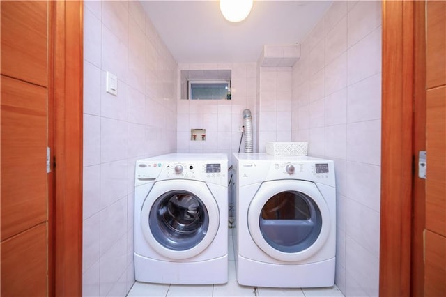 laundry area with tile walls, washer and dryer, and tile patterned floors