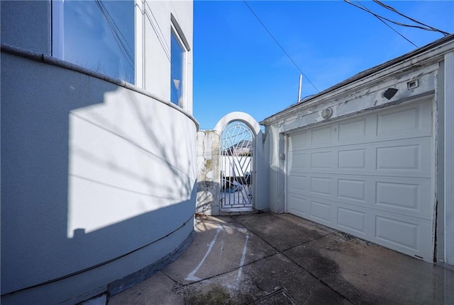 garage featuring driveway and a gate