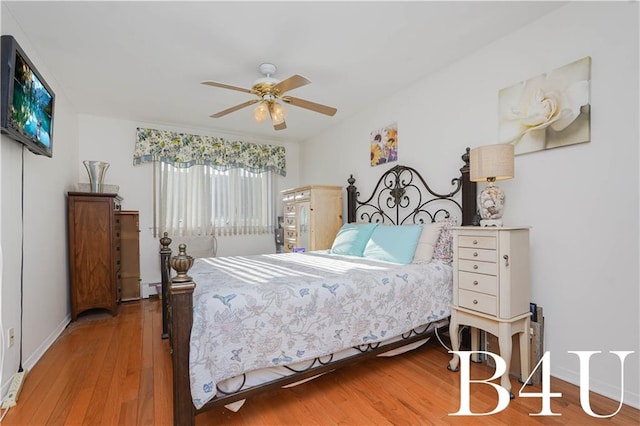 bedroom featuring ceiling fan, hardwood / wood-style floors, and a baseboard heating unit