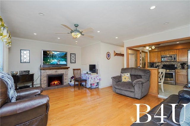 living room featuring a stone fireplace, light hardwood / wood-style flooring, ornamental molding, and ceiling fan