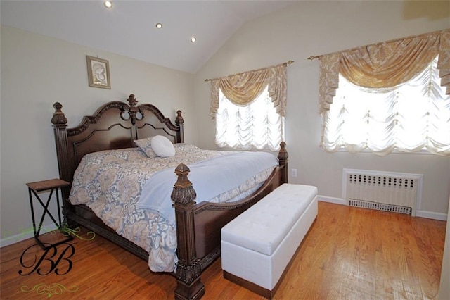 bedroom with radiator heating unit, baseboards, vaulted ceiling, and wood finished floors