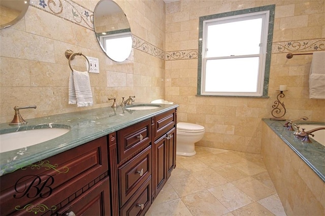 bathroom featuring a sink, tiled tub, toilet, and tile walls