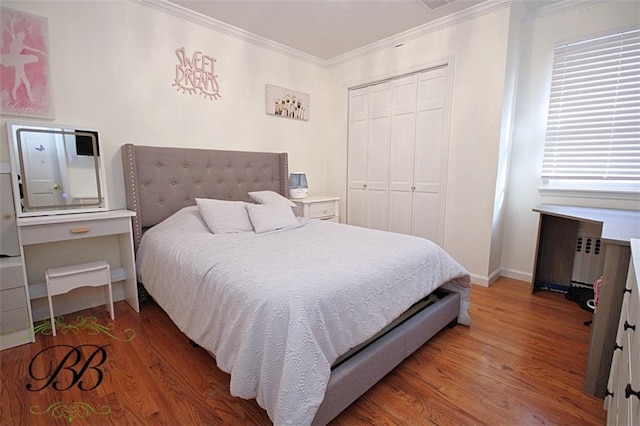 bedroom featuring a closet, crown molding, baseboards, and wood finished floors