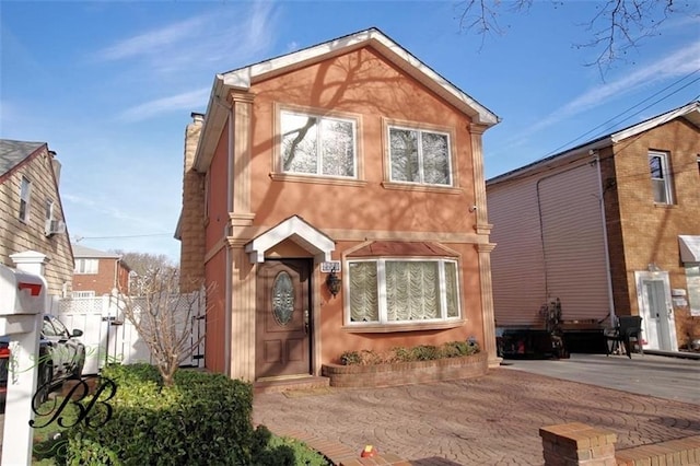 view of front of house with a chimney, fence, and stucco siding