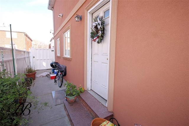 doorway to property with fence and stucco siding