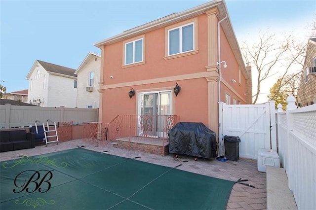 rear view of house featuring a gate, a patio area, a fenced backyard, and stucco siding