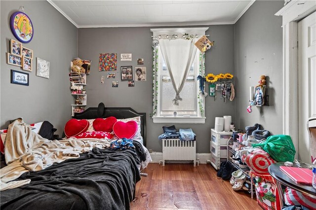 bedroom featuring hardwood / wood-style flooring, crown molding, and radiator