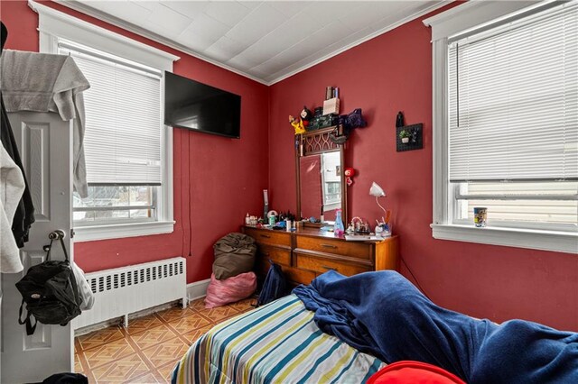 bedroom with crown molding, light parquet flooring, radiator, and multiple windows