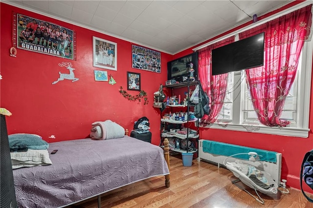 bedroom with hardwood / wood-style flooring and ornamental molding