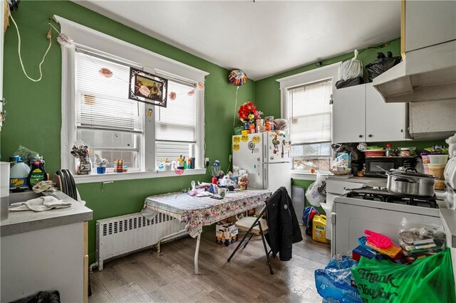 kitchen featuring white cabinetry, white fridge, radiator heating unit, and light hardwood / wood-style flooring