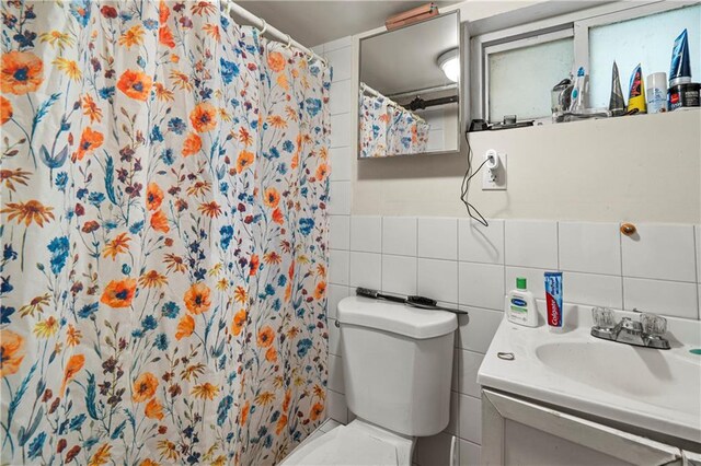 bathroom with tile walls, vanity, toilet, and a shower with shower curtain