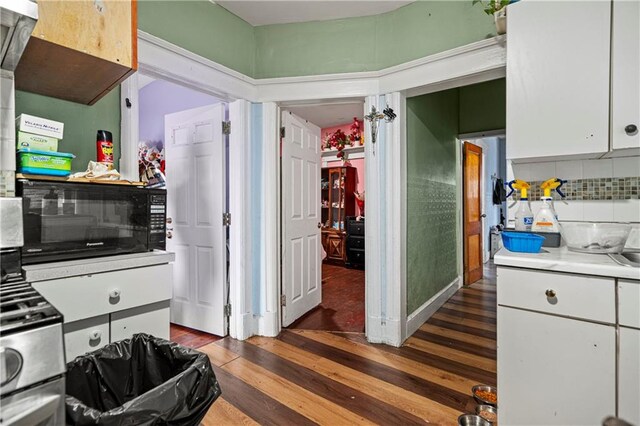 kitchen with dark wood-type flooring, decorative backsplash, and white cabinets