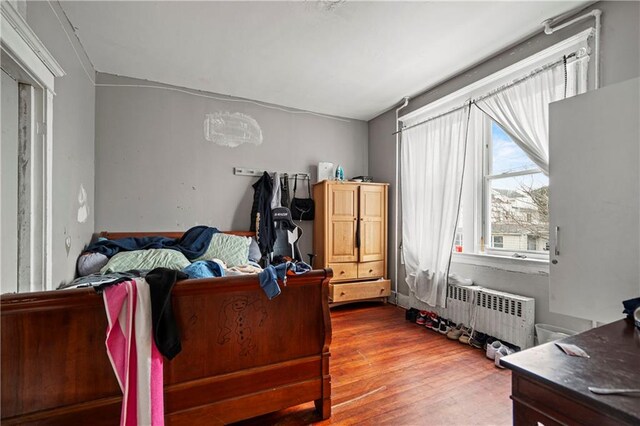 bedroom with hardwood / wood-style flooring and radiator heating unit