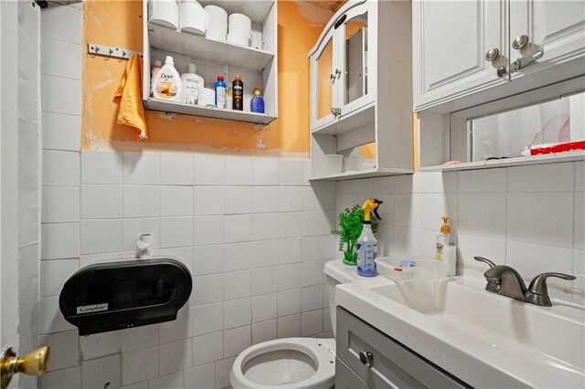 bathroom featuring tile walls, vanity, decorative backsplash, and toilet