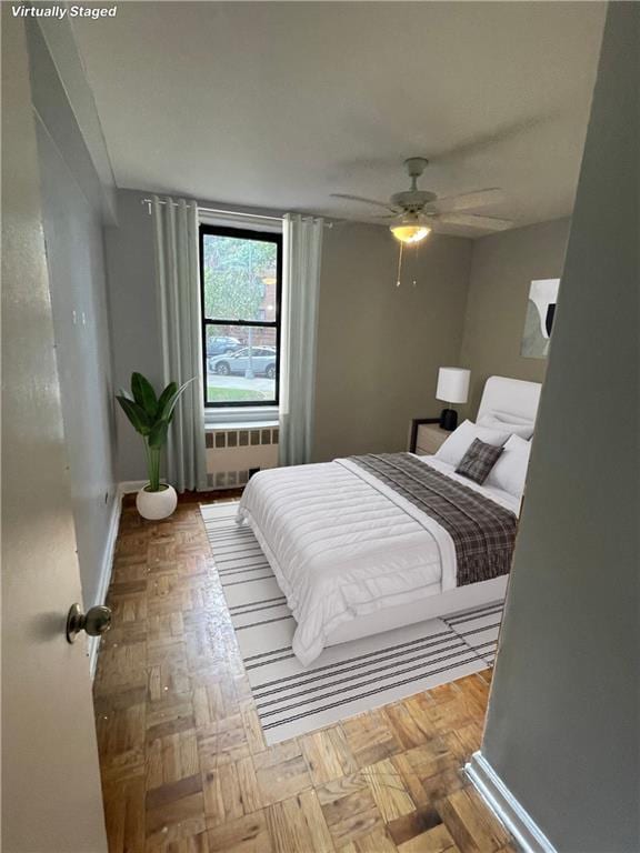 bedroom with radiator heating unit, light parquet flooring, and ceiling fan