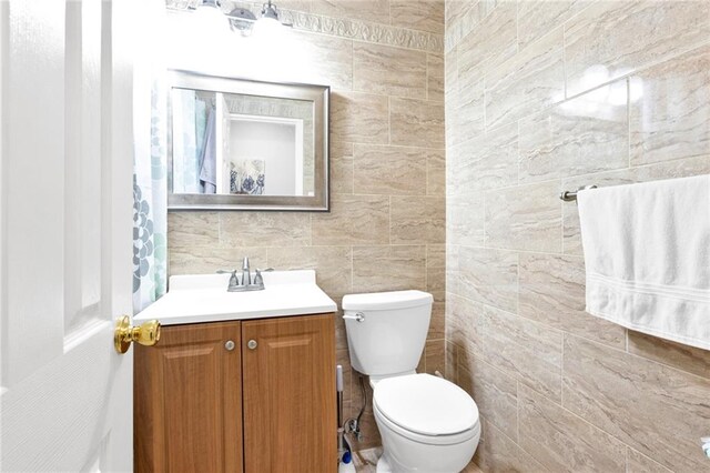 bathroom featuring vanity, tile walls, and toilet