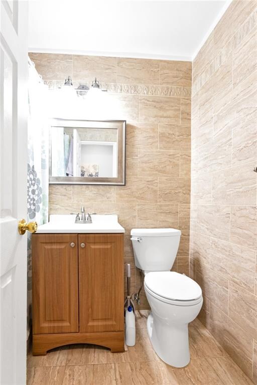 bathroom with vanity, toilet, and tile walls