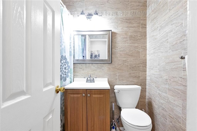 bathroom with vanity, tile walls, and toilet