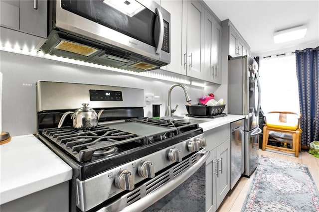 kitchen with gray cabinetry, sink, and stainless steel appliances