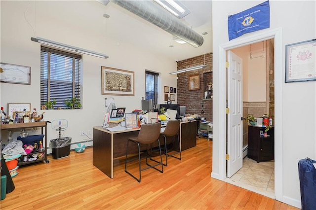 office area with light hardwood / wood-style flooring and a baseboard radiator