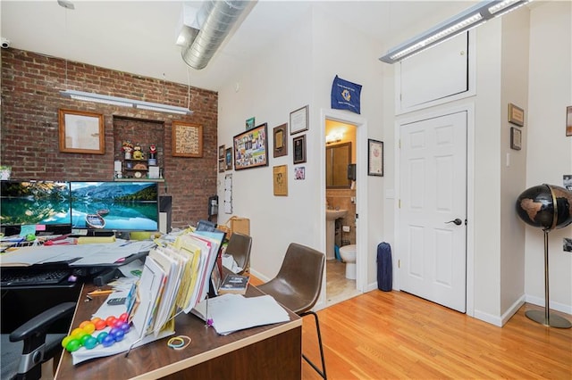 office area featuring brick wall and light wood-type flooring