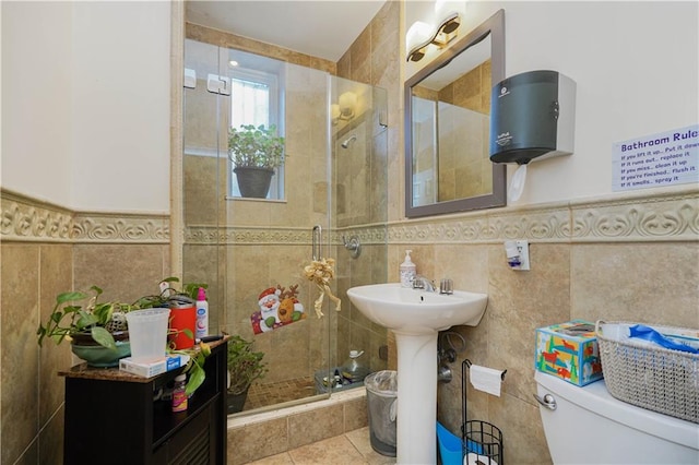 bathroom featuring sink, toilet, tile patterned flooring, and tile walls