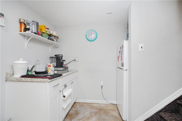 kitchen featuring white cabinets, white fridge, and light tile patterned floors