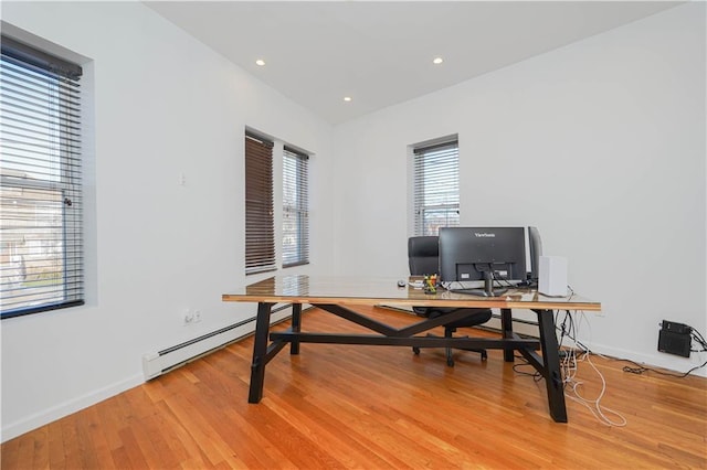 office area with light hardwood / wood-style floors and a baseboard heating unit