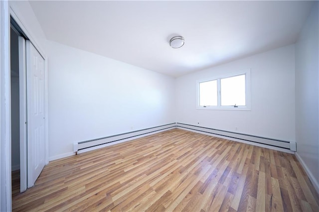 empty room with hardwood / wood-style flooring, a baseboard radiator, and a closet