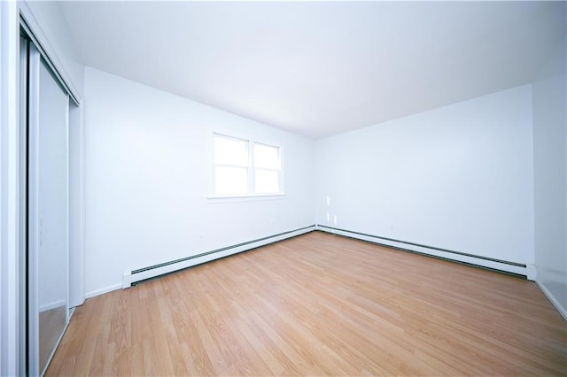 unfurnished bedroom with a baseboard radiator, a closet, and light hardwood / wood-style flooring