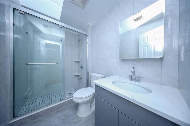 bathroom with tile walls, vanity, a shower with shower door, and toilet