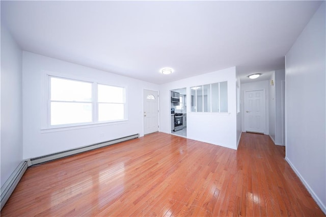 unfurnished living room featuring hardwood / wood-style floors and a baseboard heating unit