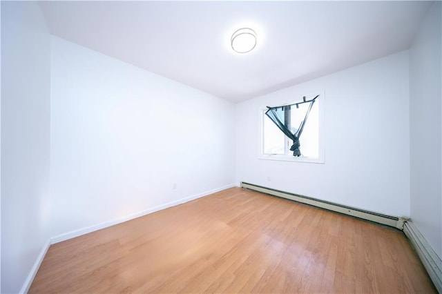 empty room with a baseboard radiator and light hardwood / wood-style floors