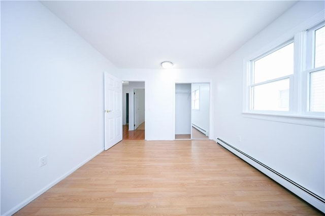 unfurnished bedroom with light hardwood / wood-style floors and a baseboard heating unit