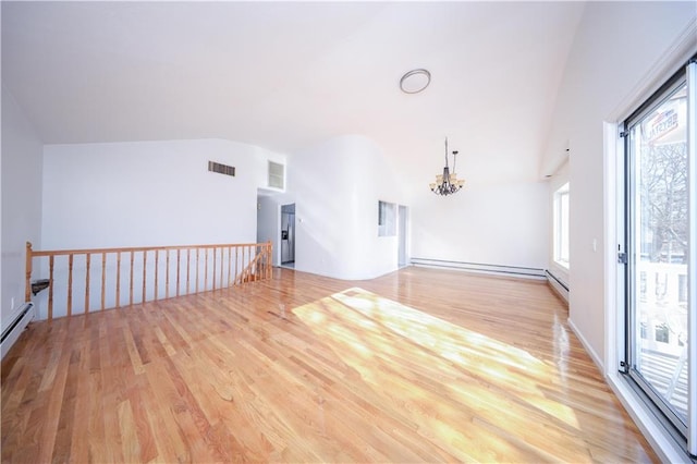 unfurnished room with lofted ceiling, a notable chandelier, and light hardwood / wood-style flooring