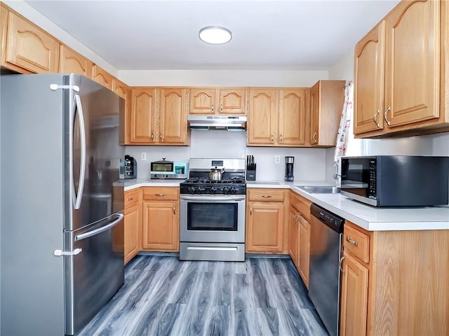 kitchen with under cabinet range hood, light brown cabinets, and stainless steel appliances