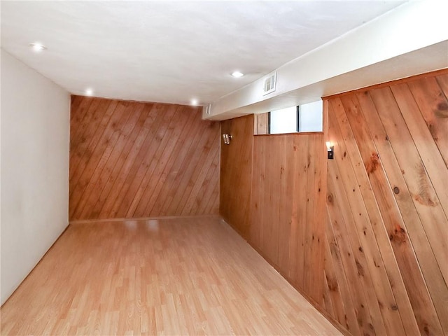 basement featuring wooden walls and light hardwood / wood-style floors