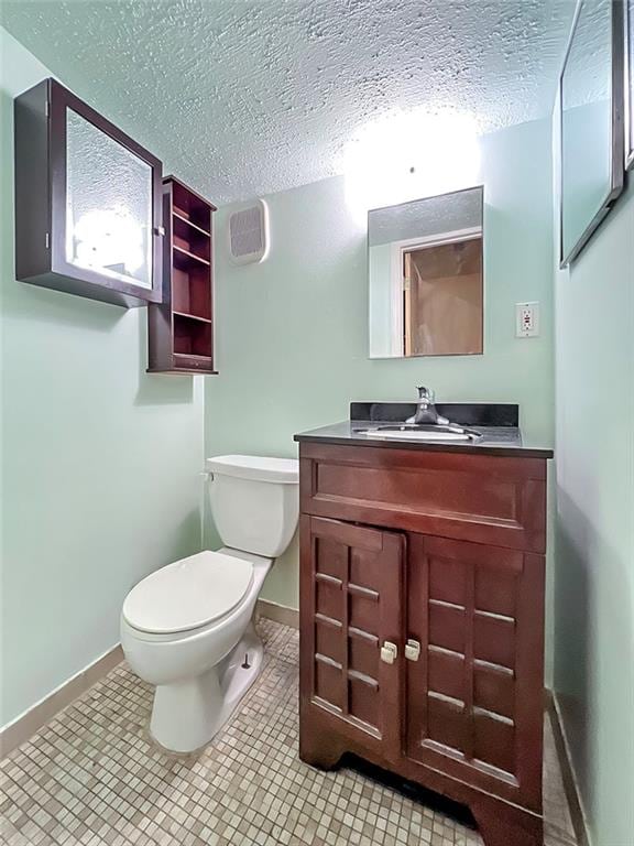 bathroom featuring tile patterned flooring, vanity, a textured ceiling, and toilet