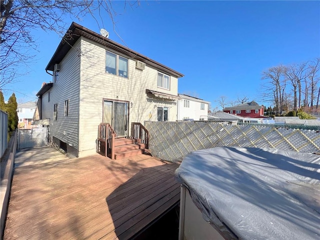 rear view of property with fence, a wall mounted air conditioner, and a wooden deck