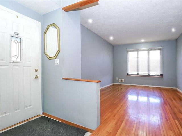 foyer with recessed lighting, baseboards, hardwood / wood-style flooring, and visible vents