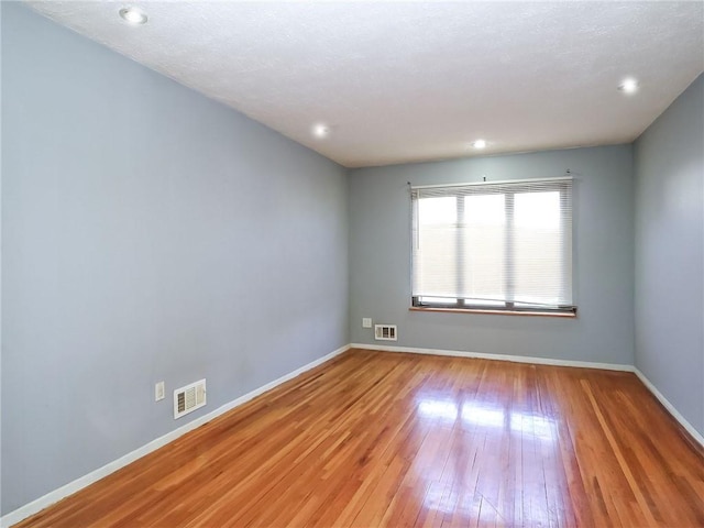 spare room featuring visible vents, baseboards, and wood finished floors
