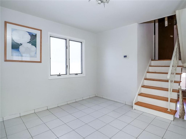 unfurnished room with light tile patterned floors and stairway