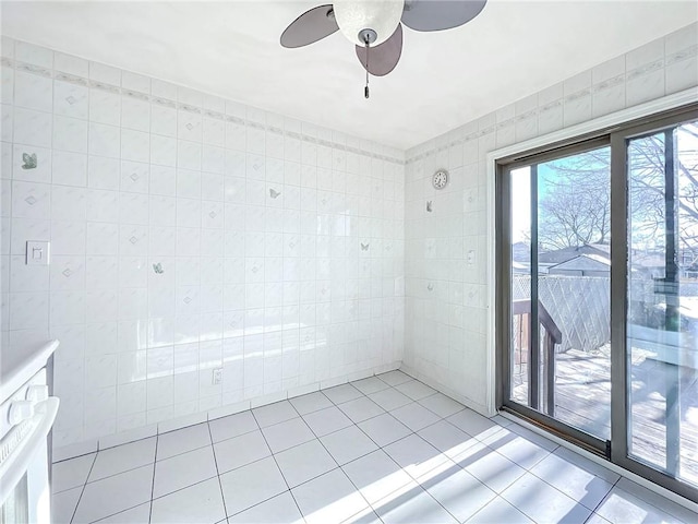 unfurnished room featuring light tile patterned floors, tile walls, and a ceiling fan